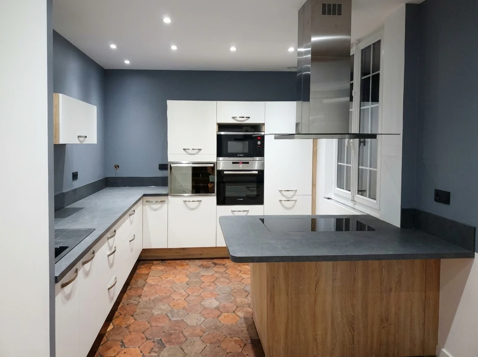 Cuisine moderne en L avec îlot central, murs gris ardoise, carrelage tomettes hexagonales terracotta
