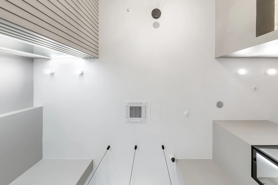 Salon lumineux avec plafond blanc orné de deux rosaces en plâtre à motif concentrique en relief